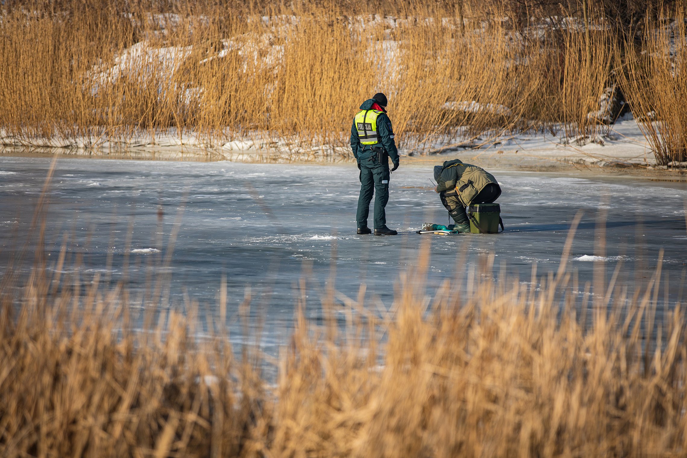 pareigūnais tikrina žveją ant ledo