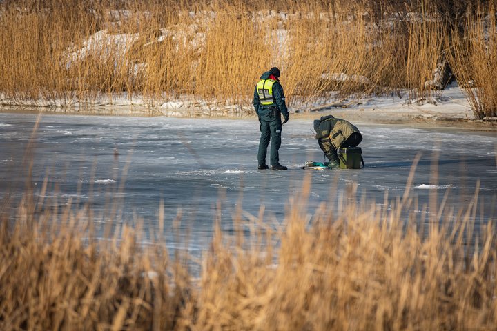 pareigūnais tikrina žveją ant ledo