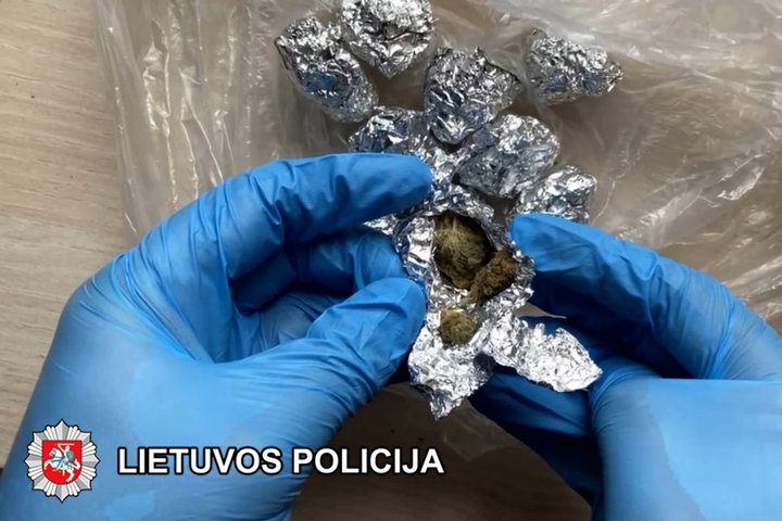 rankose laikomas folijos lankstinukas su narkotine medžiaga